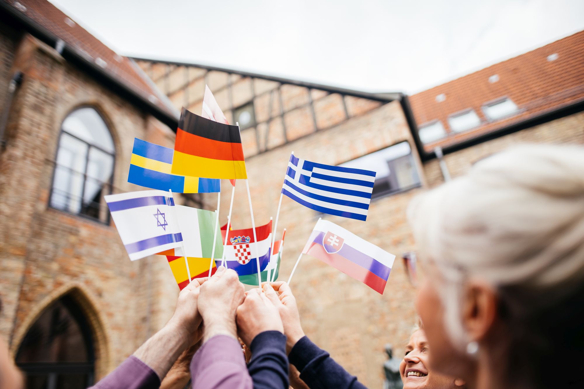 Hochschulvertreter:innen halten Fähnchen mit den Flaggen verschiedener europäischer Länder