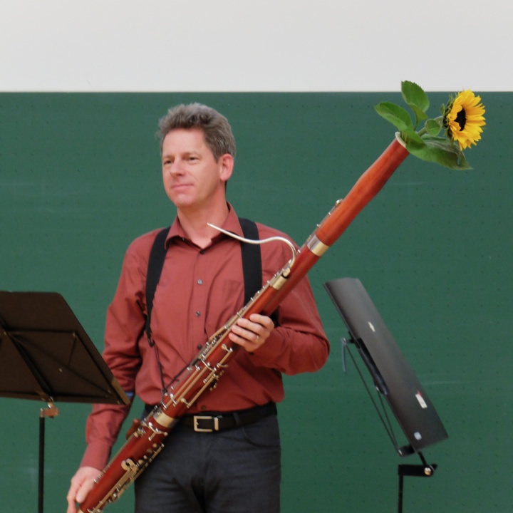 Musician Enno Baars with bassoon from which a sunflower is sticking out.