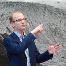 Prof. Dirk Pflüger gestikuliert vor Poster des Antisana-Gletschers.