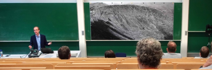 Blick über das Auditorium zu Professor Dirk Pflüger und tafelfüllendem Poster des Antisana-Gletschers.